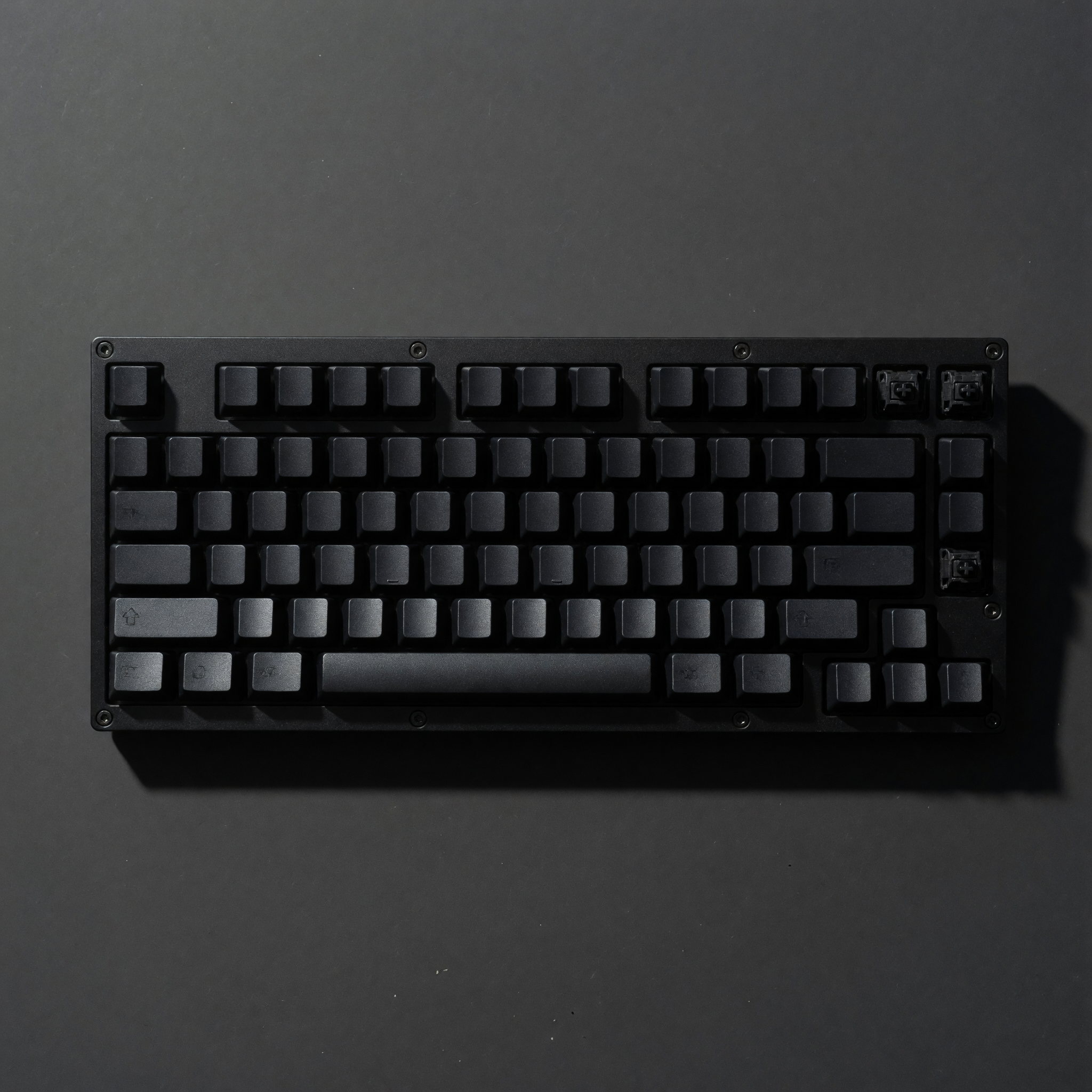A minimalist matte-black mechanical keyboard, top-down studio shot